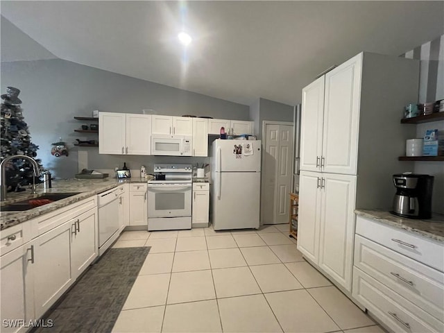 kitchen with sink, white cabinets, light tile patterned floors, light stone countertops, and white appliances