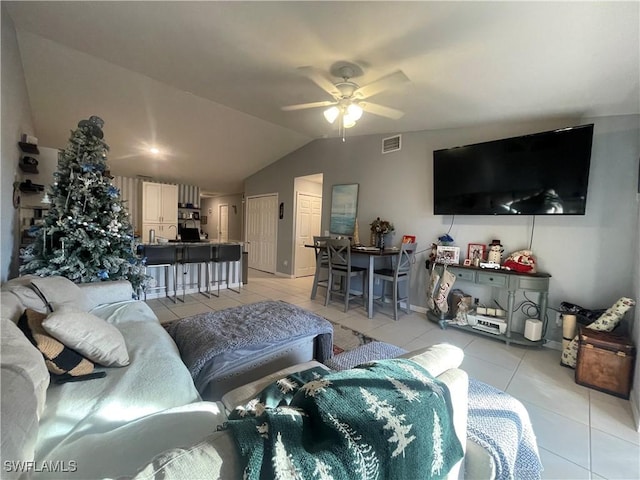 living room with ceiling fan, vaulted ceiling, and light tile patterned floors