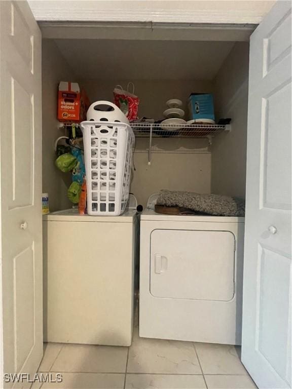 clothes washing area featuring light tile patterned flooring and washer and dryer