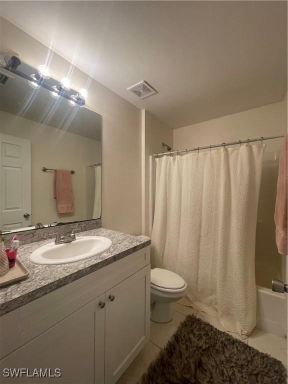 full bathroom featuring shower / bath combination with curtain, vanity, tile patterned floors, and toilet