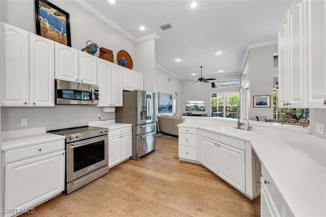 kitchen with appliances with stainless steel finishes, sink, white cabinets, kitchen peninsula, and light wood-type flooring