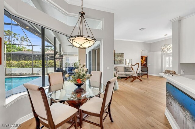 dining room with light hardwood / wood-style flooring, ornamental molding, and a healthy amount of sunlight