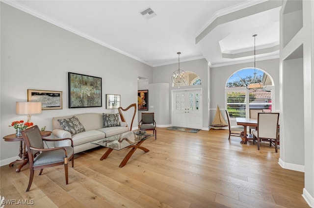 living room featuring ornamental molding, light wood-type flooring, and a chandelier