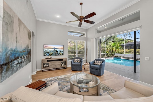 living room with ceiling fan, baseboards, wood finished floors, and crown molding