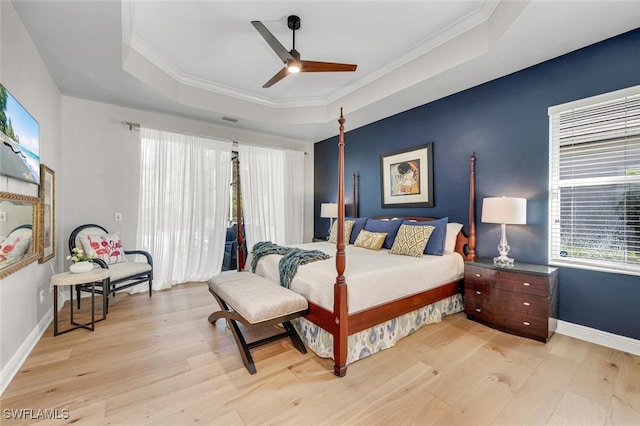 bedroom featuring ornamental molding, a raised ceiling, and light wood-type flooring