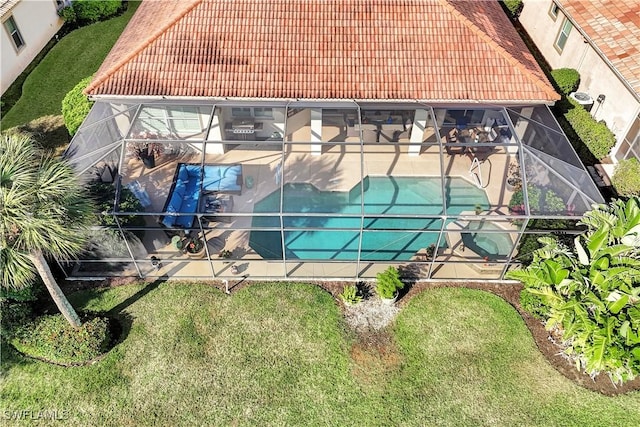 view of swimming pool with a lawn, a patio, and glass enclosure