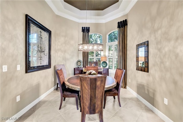 tiled dining area featuring a towering ceiling, an inviting chandelier, and a tray ceiling