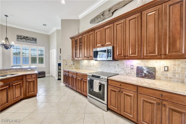 kitchen with pendant lighting, stainless steel appliances, light stone counters, tasteful backsplash, and ornamental molding