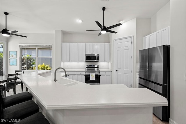 kitchen with white cabinets, appliances with stainless steel finishes, sink, and a large island with sink