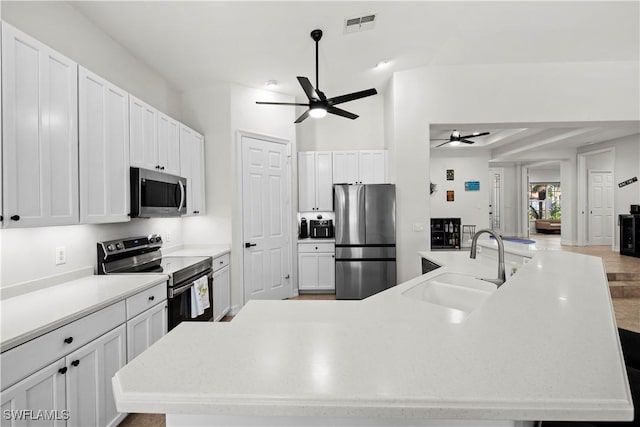 kitchen with a spacious island, white cabinetry, appliances with stainless steel finishes, and sink