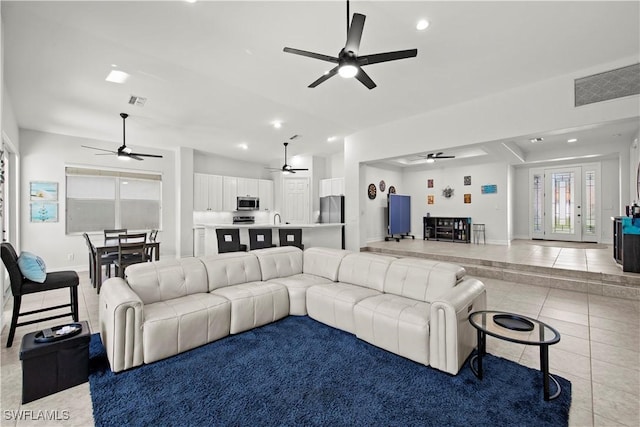 living room with light tile patterned flooring, ceiling fan, vaulted ceiling, and sink