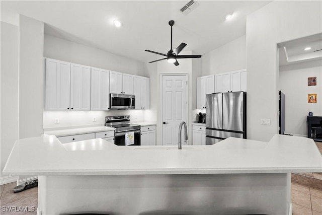 kitchen with white cabinets, stainless steel appliances, and a large island with sink