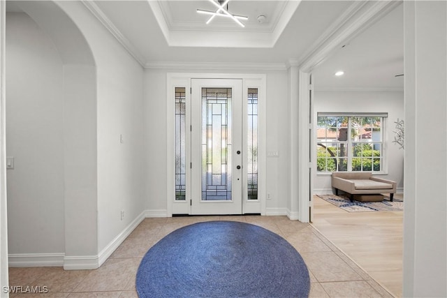 foyer entrance featuring light tile patterned floors, crown molding, and a raised ceiling