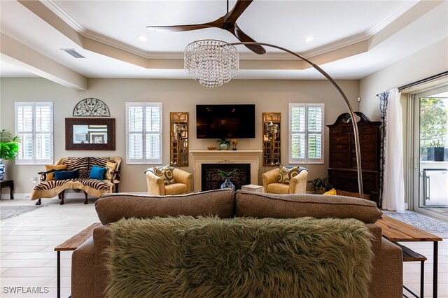 living room featuring crown molding, a tray ceiling, ceiling fan, and light wood-type flooring