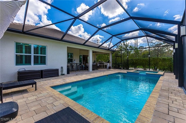 view of swimming pool with glass enclosure, a patio, and a pool with connected hot tub