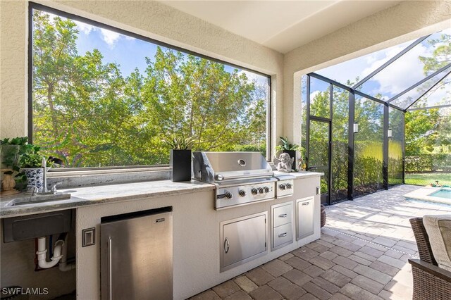 view of patio with area for grilling, sink, a lanai, and exterior kitchen