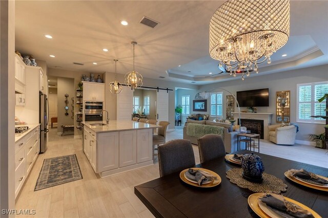 dining room with sink, a notable chandelier, a tray ceiling, and a barn door