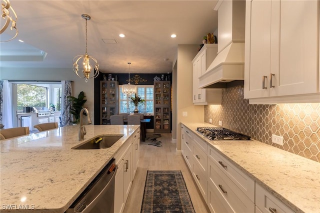 kitchen with stainless steel appliances, white cabinetry, a sink, light stone countertops, and premium range hood