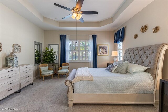 carpeted bedroom featuring ceiling fan and a tray ceiling