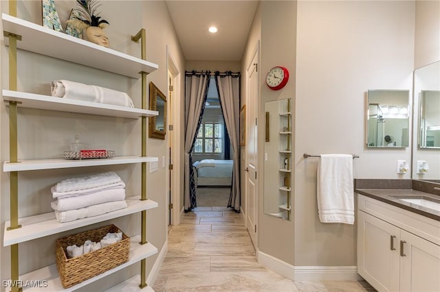 ensuite bathroom featuring recessed lighting, baseboards, connected bathroom, and vanity