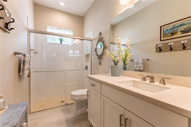 full bath with wood finished floors, a shower stall, toilet, and vanity