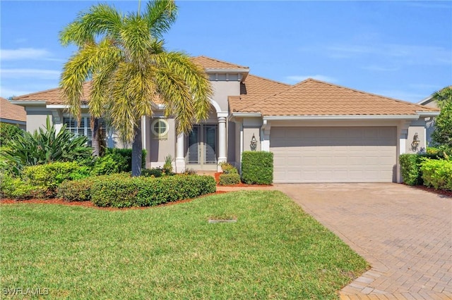 mediterranean / spanish house with a garage and a front lawn