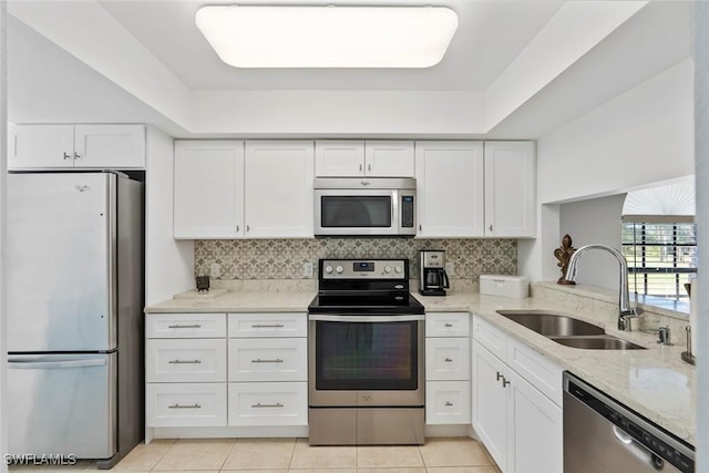 kitchen featuring backsplash, appliances with stainless steel finishes, white cabinets, a sink, and light stone countertops