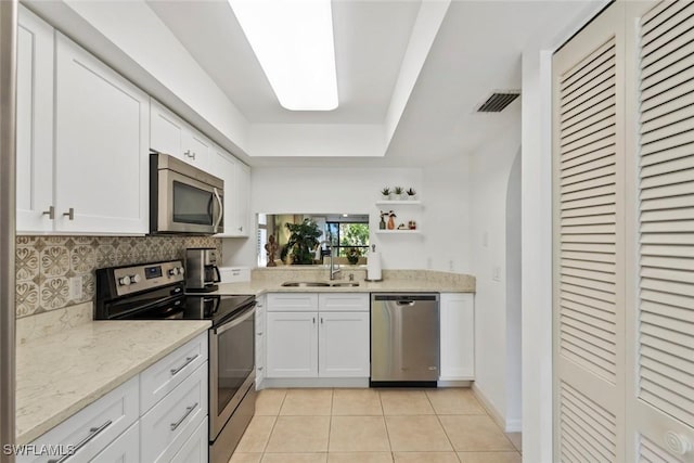 kitchen with light tile patterned floors, stainless steel appliances, a sink, visible vents, and white cabinets