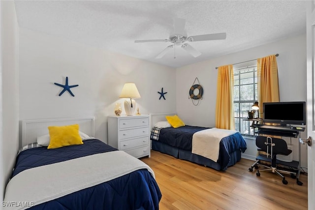 bedroom featuring light wood-style flooring, a ceiling fan, and a textured ceiling