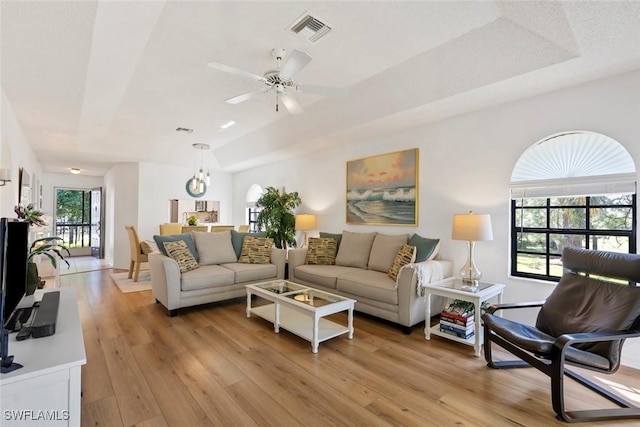 living area featuring light wood-style floors, visible vents, and a ceiling fan