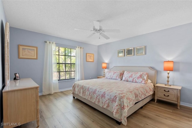 bedroom featuring a ceiling fan, baseboards, a textured ceiling, and light wood-style floors