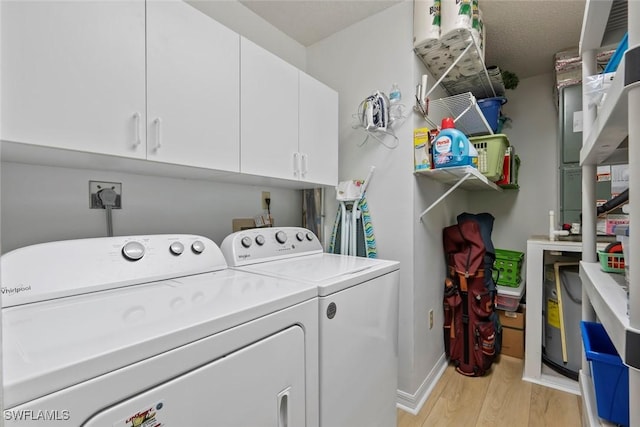 laundry area with cabinet space, baseboards, separate washer and dryer, and light wood finished floors