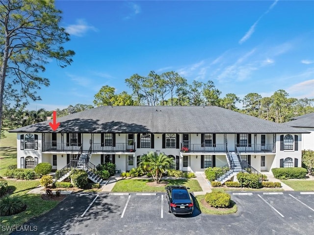 view of property featuring uncovered parking and stairway