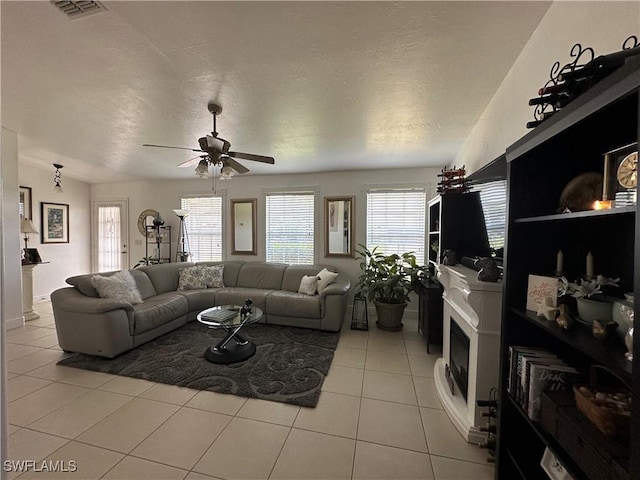 tiled living room with ceiling fan and a textured ceiling