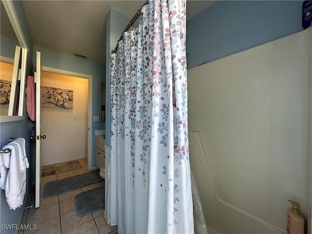 bathroom featuring tile patterned floors, toilet, and walk in shower