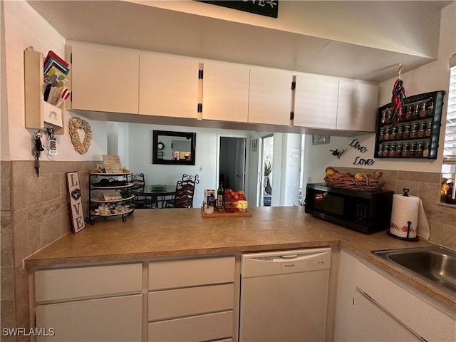 kitchen featuring dishwasher, sink, tile walls, and white cabinets