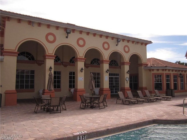 rear view of property with a community pool and a patio