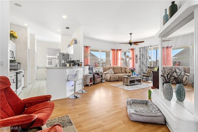 living room with ceiling fan, plenty of natural light, and light hardwood / wood-style floors