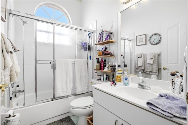 full bathroom featuring vanity, shower / bath combination with glass door, and toilet