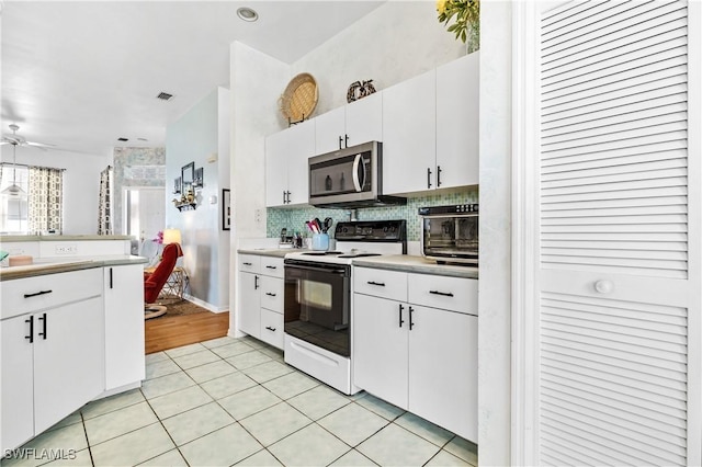 kitchen featuring electric range oven, pendant lighting, white cabinets, decorative backsplash, and light tile patterned floors