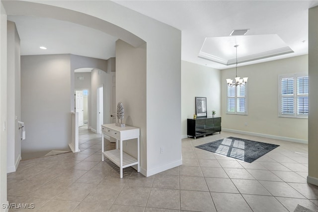 foyer featuring a tray ceiling, arched walkways, light tile patterned floors, visible vents, and baseboards