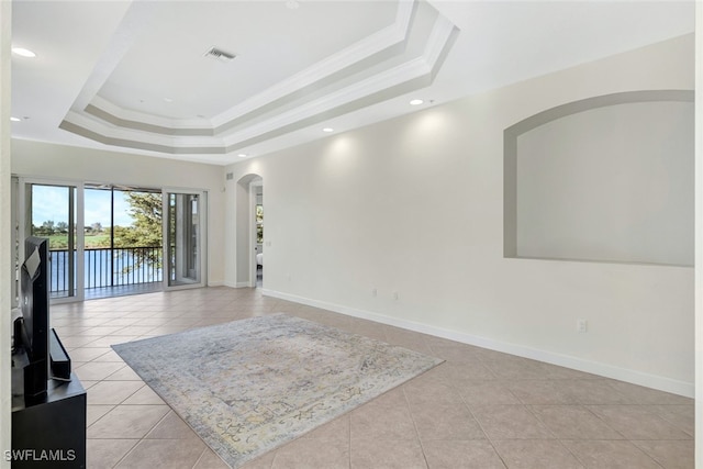 spare room with a raised ceiling, ornamental molding, and light tile patterned floors