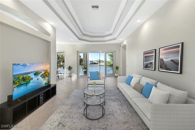 tiled living room with ornamental molding and a raised ceiling