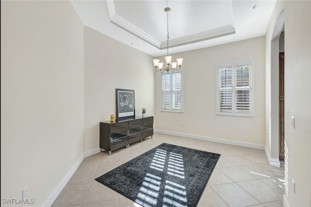 entryway with a tray ceiling, a notable chandelier, ornamental molding, tile patterned flooring, and baseboards