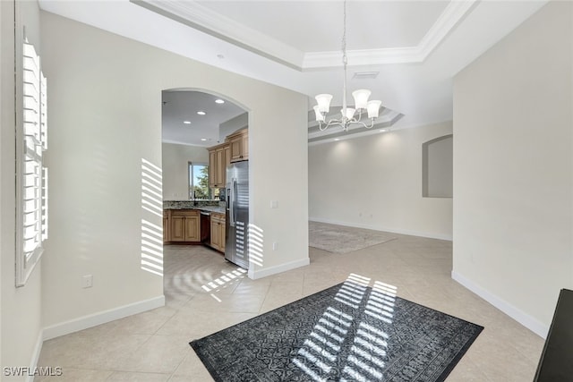 tiled foyer with crown molding, a raised ceiling, and a chandelier