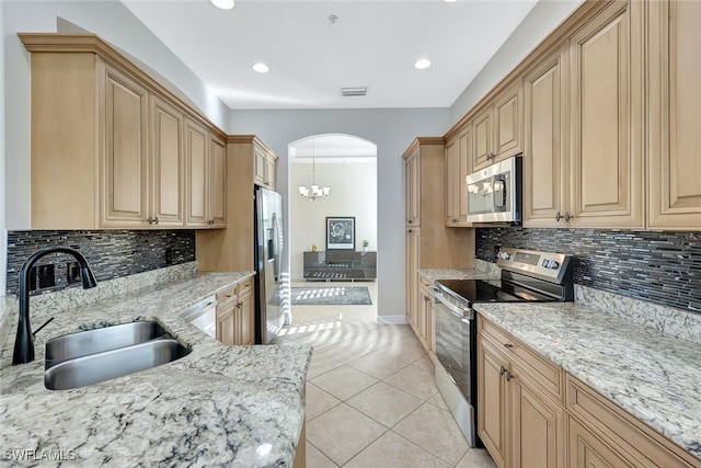 kitchen featuring sink, a chandelier, hanging light fixtures, appliances with stainless steel finishes, and light stone countertops