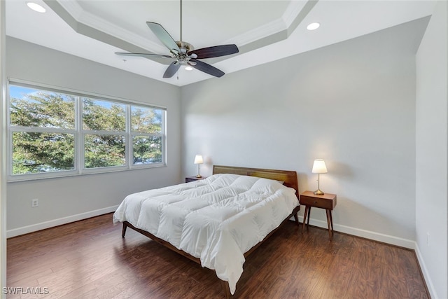 bedroom featuring crown molding, a tray ceiling, dark hardwood / wood-style floors, and ceiling fan