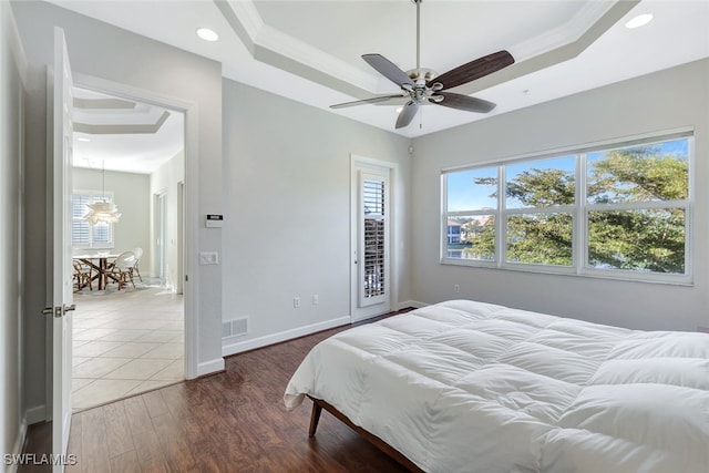 bedroom featuring visible vents, a raised ceiling, wood finished floors, and ornamental molding