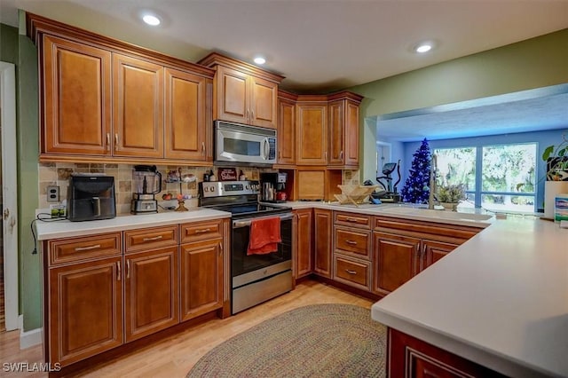 kitchen featuring stainless steel appliances, tasteful backsplash, sink, and light hardwood / wood-style flooring