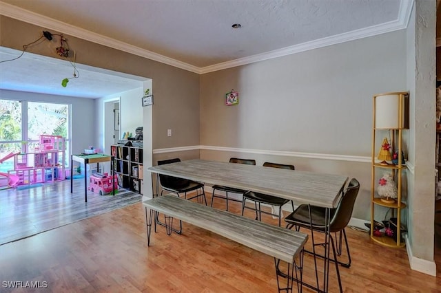 dining area with ornamental molding and light hardwood / wood-style floors